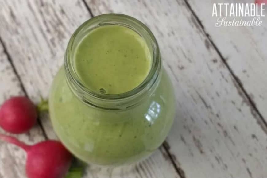 This healthy radish leaf salad dressing recipe features radish greens. Use it to top your favorite green salad or serve it as a dip with fresh veggies. 奶油绿色的沙拉酱在一个玻璃罐里,旁边放着两个萝卜