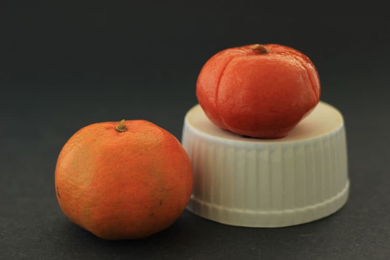 Preserved oranges, lemons, and tangerines, are great in marinades &salad dressings. Salted citrus an easy way to preserve citrus flavor for use in recipes. 一个新鲜的橘子,一个在黑色背景下保存的橘子