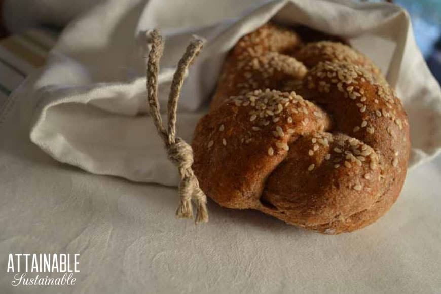 Wondering how to keep homemade bread fresh? Here's how to store homemade bread in DIY linen bread bags so it lasts longer. Here's how to make a bag from thrifted linen in 15 minutes! 装在亚麻面包袋里的一条编织面包