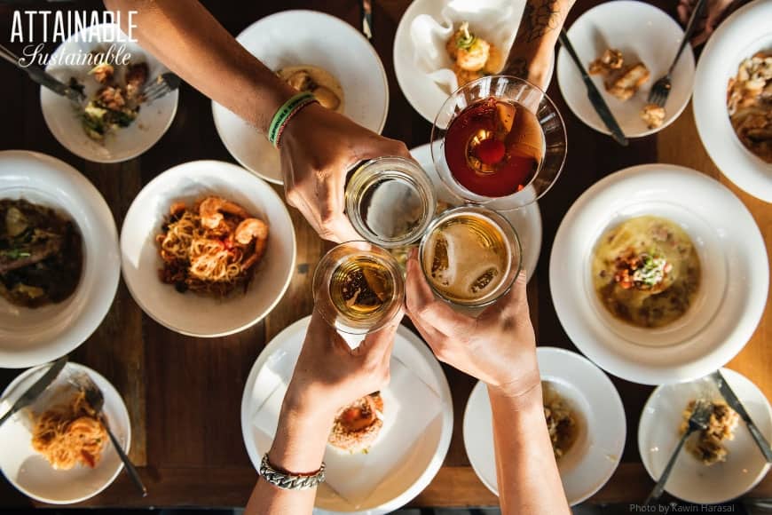 From disposable plates & cups to party decor, the trash generated by hosting a party can be mind-boggling. Here's how to make some eco-friendly adjustments! 四双手从上往下敬酒,白色的盘子里盛满了食物