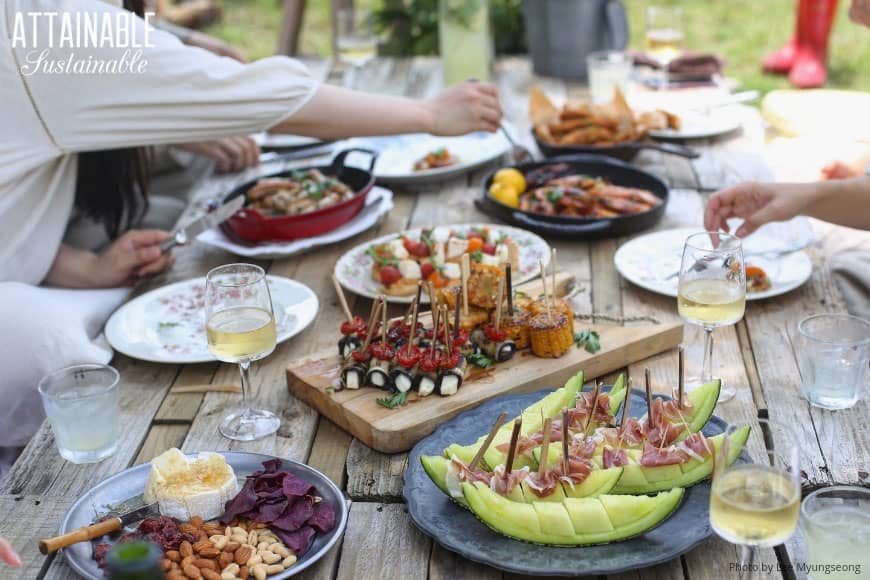 From disposable plates & cups to party decor, the trash generated by hosting a party can be mind-boggling. Here's how to make some eco-friendly adjustments! 户外聚会,食物放在木桌上
