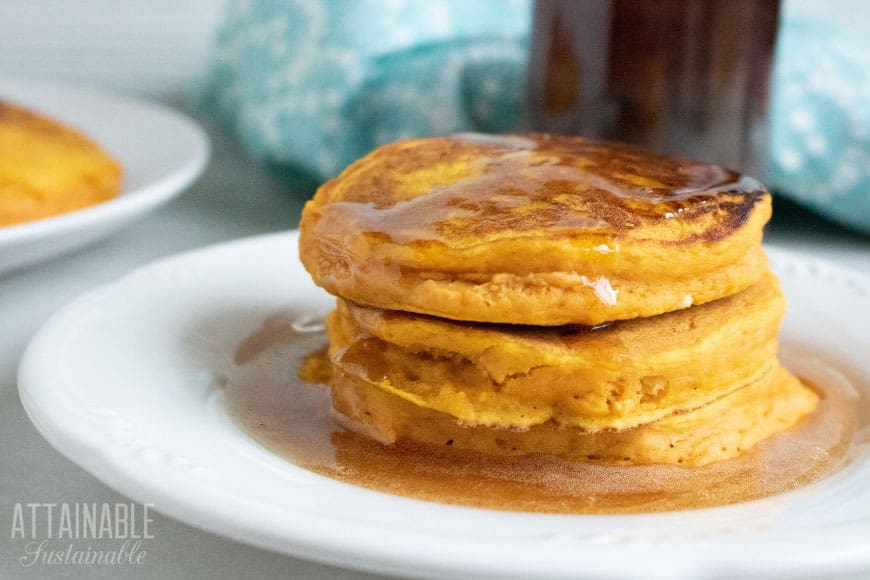 Stack of three easy pumpkin pancakes on a white plate with syrup