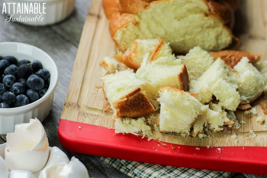 Challah面包立方体在一个木切板用蓝莓在附近的一个白色容器